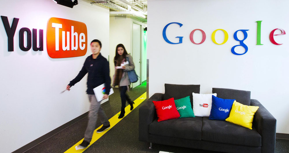 File photo shows people walking by a YouTube sign at the new Google office in Toronto
