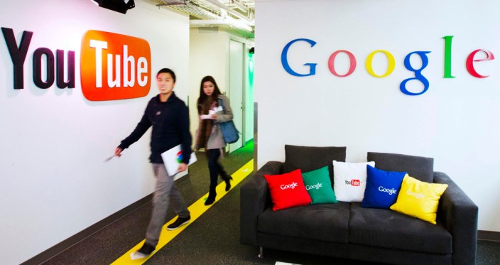 File photo shows people walking by a YouTube sign at the new Google office in Toronto